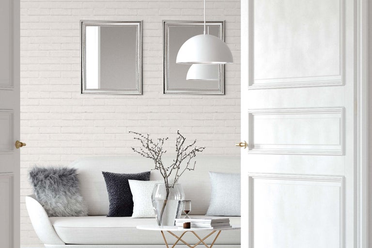 Espace de vie lumineux avec canapé, table, décoration, deux miroirs, une suspension et une porte ouverte