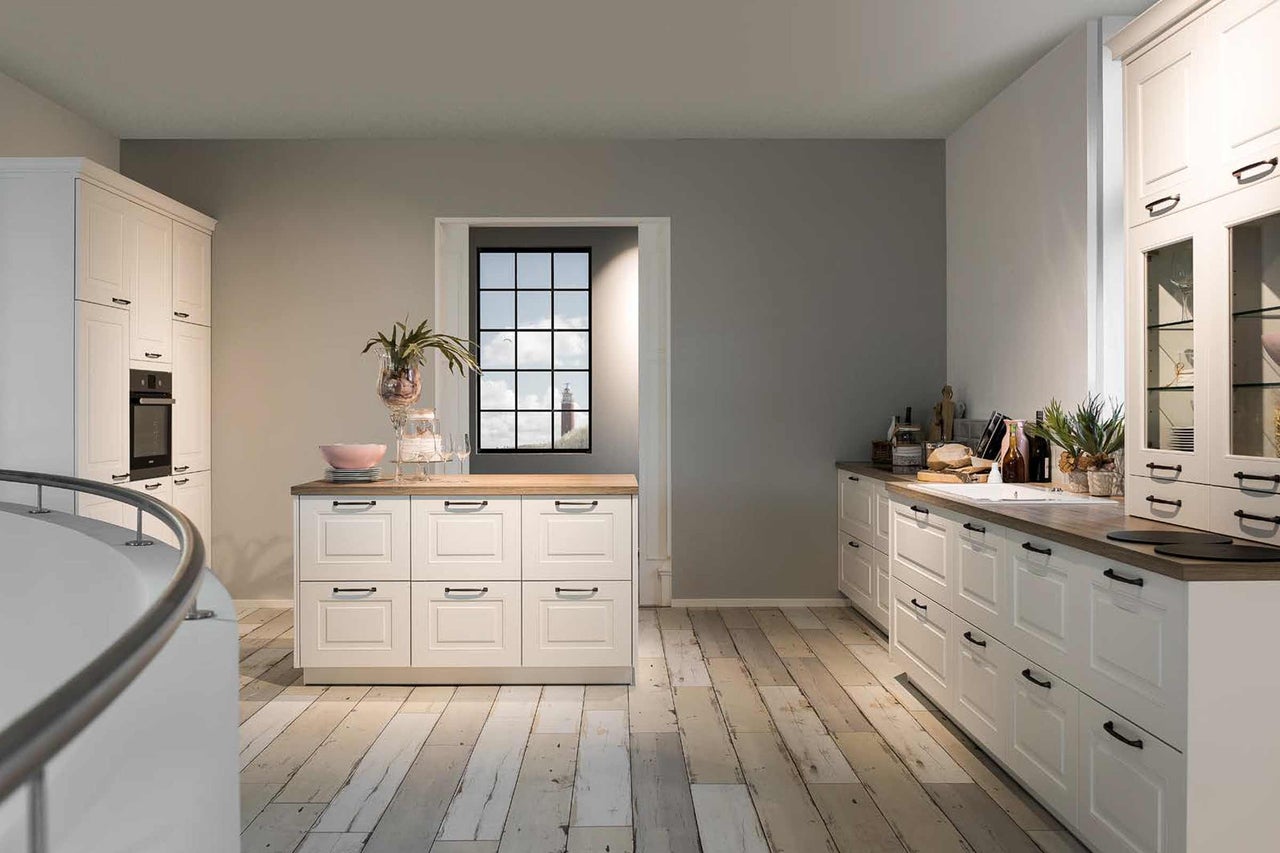 Cuisine lumineuse avec armoires blanches, plancher en bois et fenêtre avec vue sur un phare