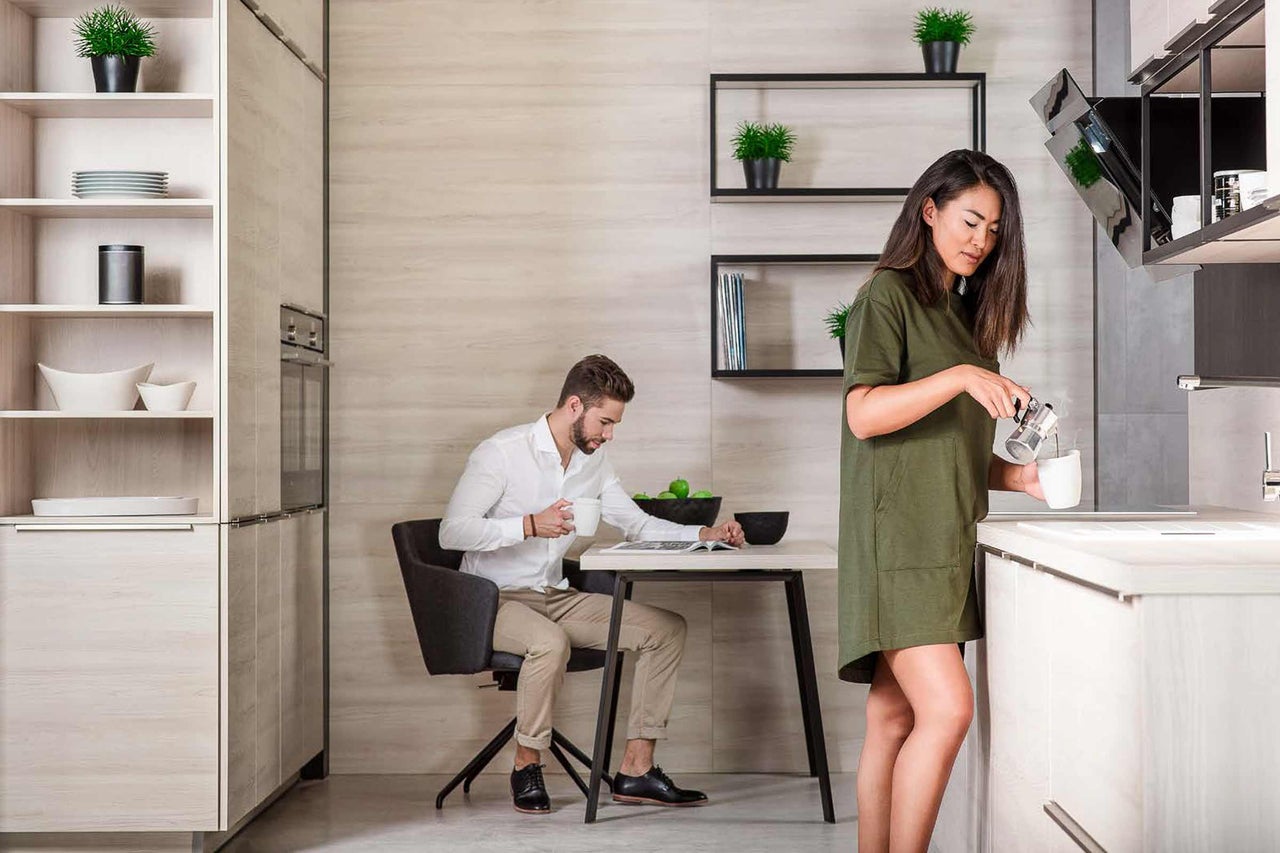 Cuisine claire avec un homme à table et une femme préparant du café
