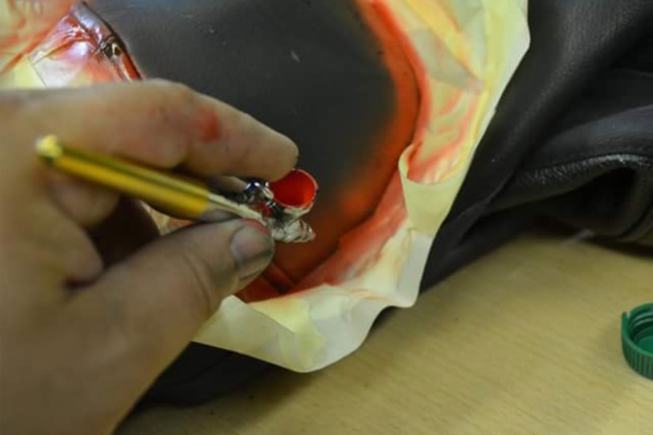 Gros plan d'une main qui vaporise de la peinture sur un objet avec un pistolet aérographe
