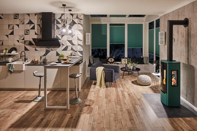 Salon lumineux avec cuisine, coin salon près de la fenêtre, poêle à bois et plancher en bois.