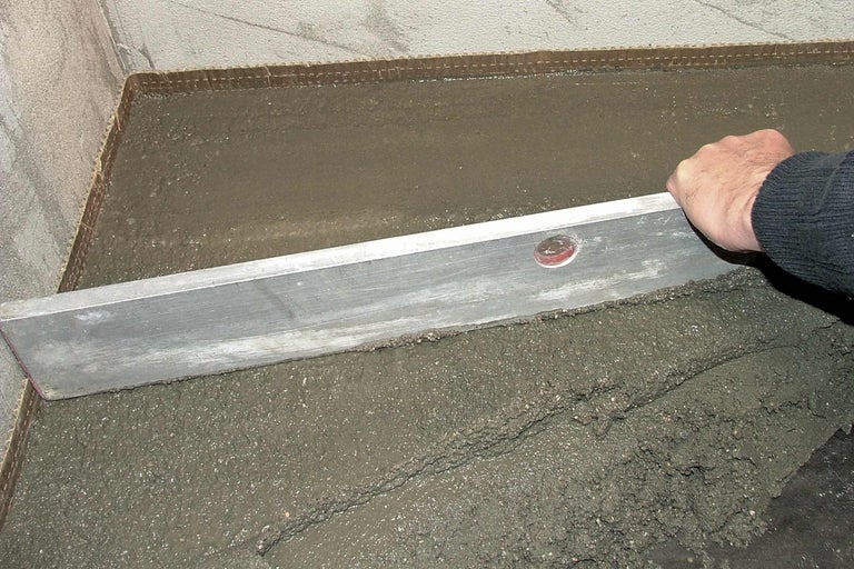 Ausgleichsmasse wird mit einer Richtlatte geglättet