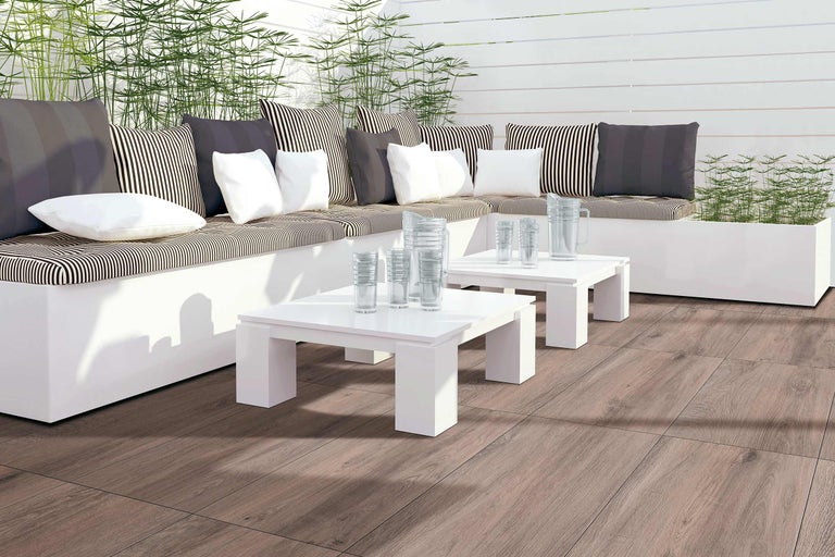 Terrasse avec coin salon, coussins, tables, verres et plancher en bois