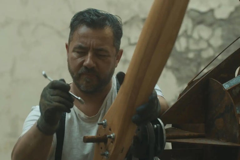 Mann befestigt mit einem Schraubenschlüssel einen Holzpropeller.