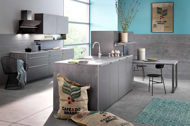 Cuisine moderne avec îlot de cuisson, table à manger et chaises dans une pièce lumineuse.