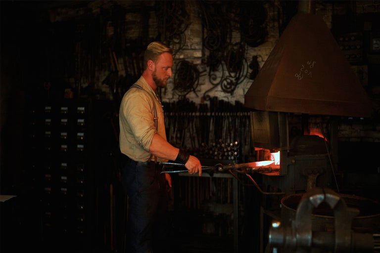 Schmied bearbeitet glühendes Metall in der Schmiede