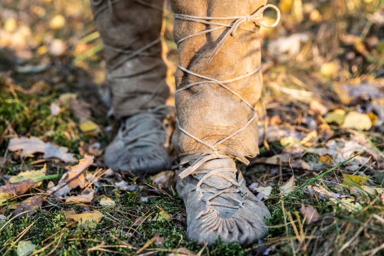 Nahaufnahme von Beinen in Ledergamaschen und Mokassins im Freien.