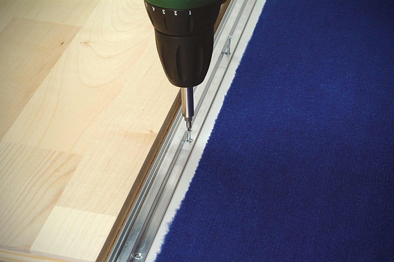 Montage d'une barre de moquette avec un tournevis sans fil sur un plancher en bois