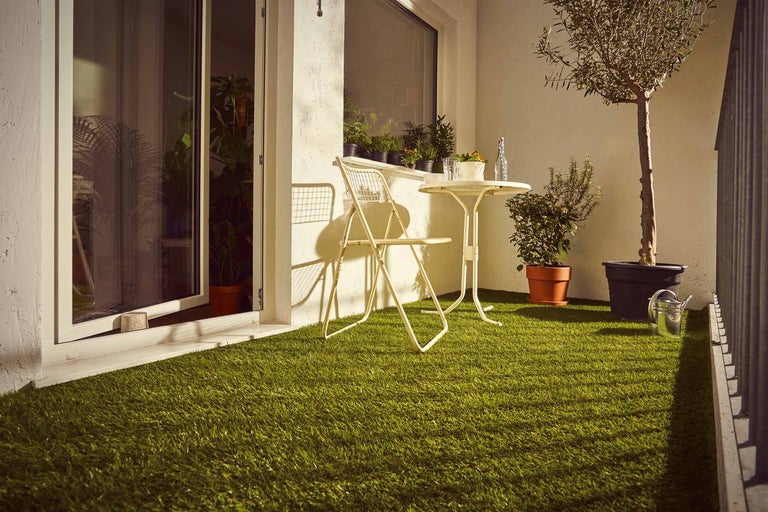 Balcon avec gazon synthétique, chaise, table et plantes
