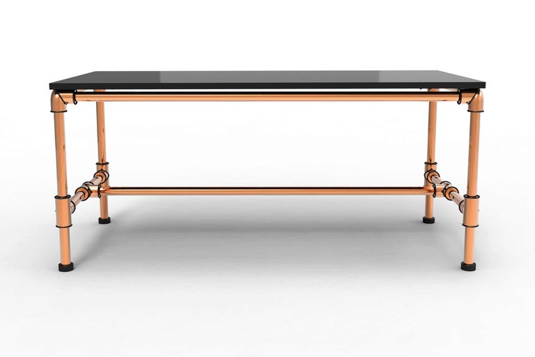 Table avec plateau noir et structure en tube de cuivre