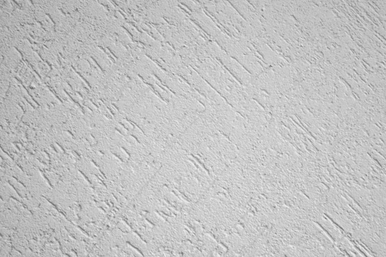 Gros plan d'un mur avec une texture d'enduit gratté.