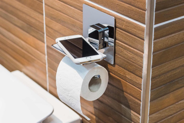 Porte-papier toilette avec tablette et téléphone portable dans la salle de bains.
