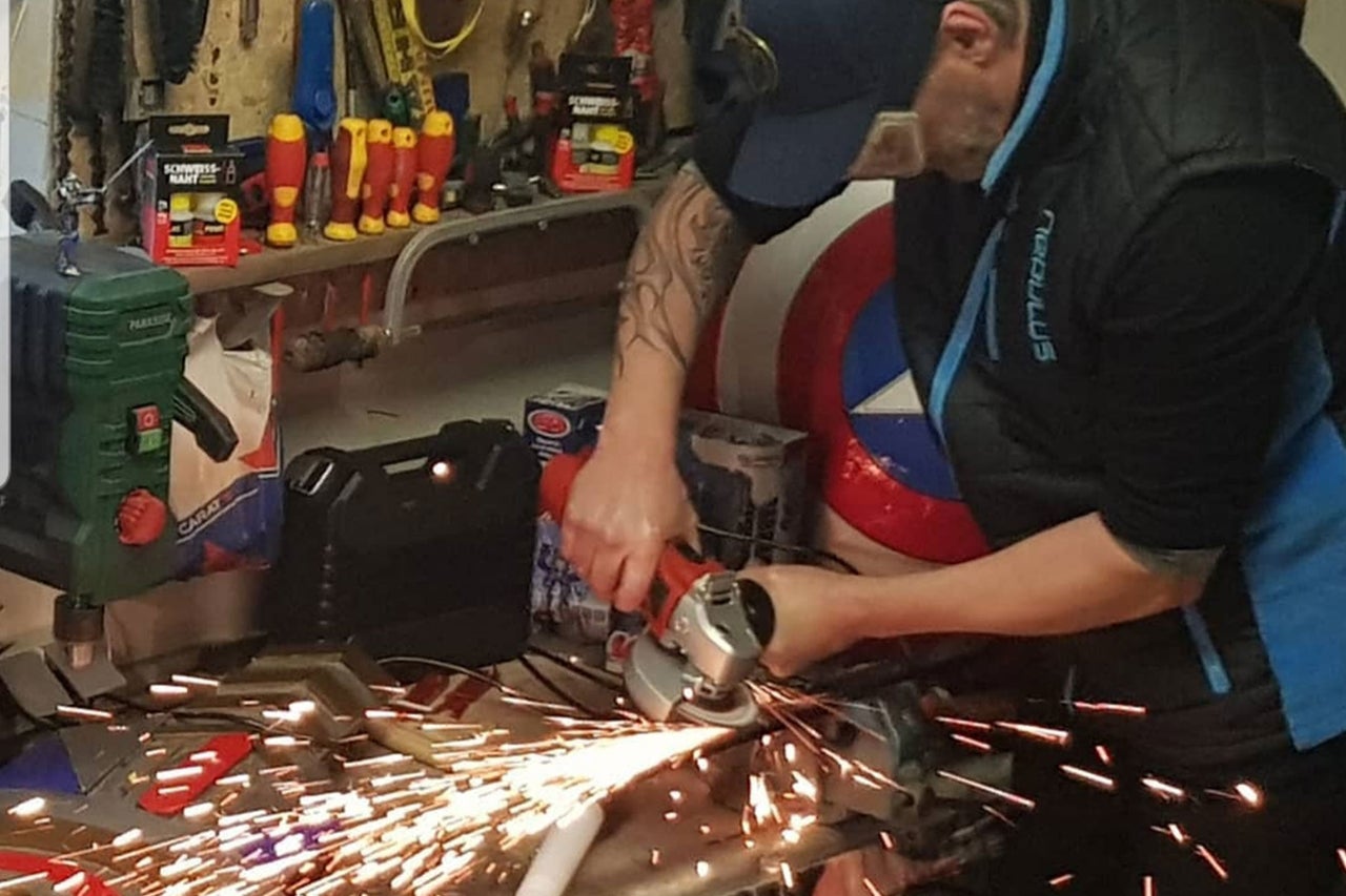 Un homme utilise une meuleuse d'angle dans un atelier, avec des étincelles