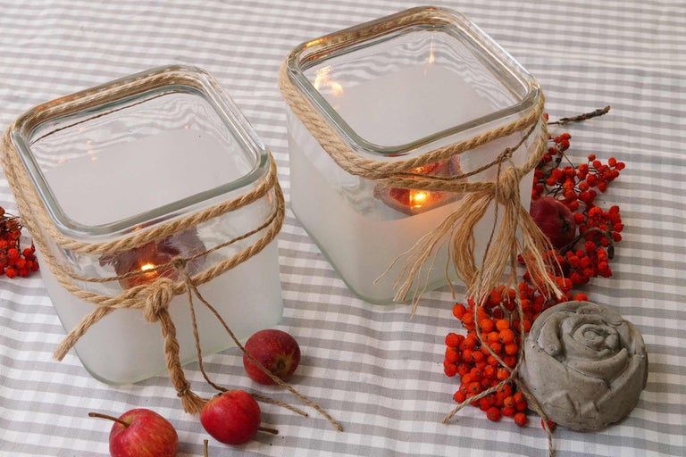 Dekorative Glaswindlichter mit Juteseil und herbstlicher Dekoration auf Tischdecke