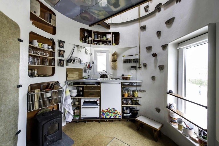 Einrichtung einer Küche mit Kochstelle, Spüle, Regalen und Kletterwand