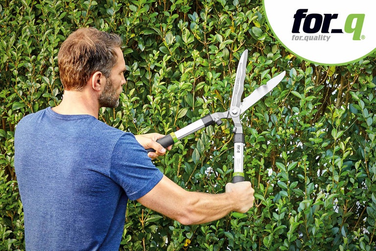 Un homme taille une haie avec un taille-haie de for_q