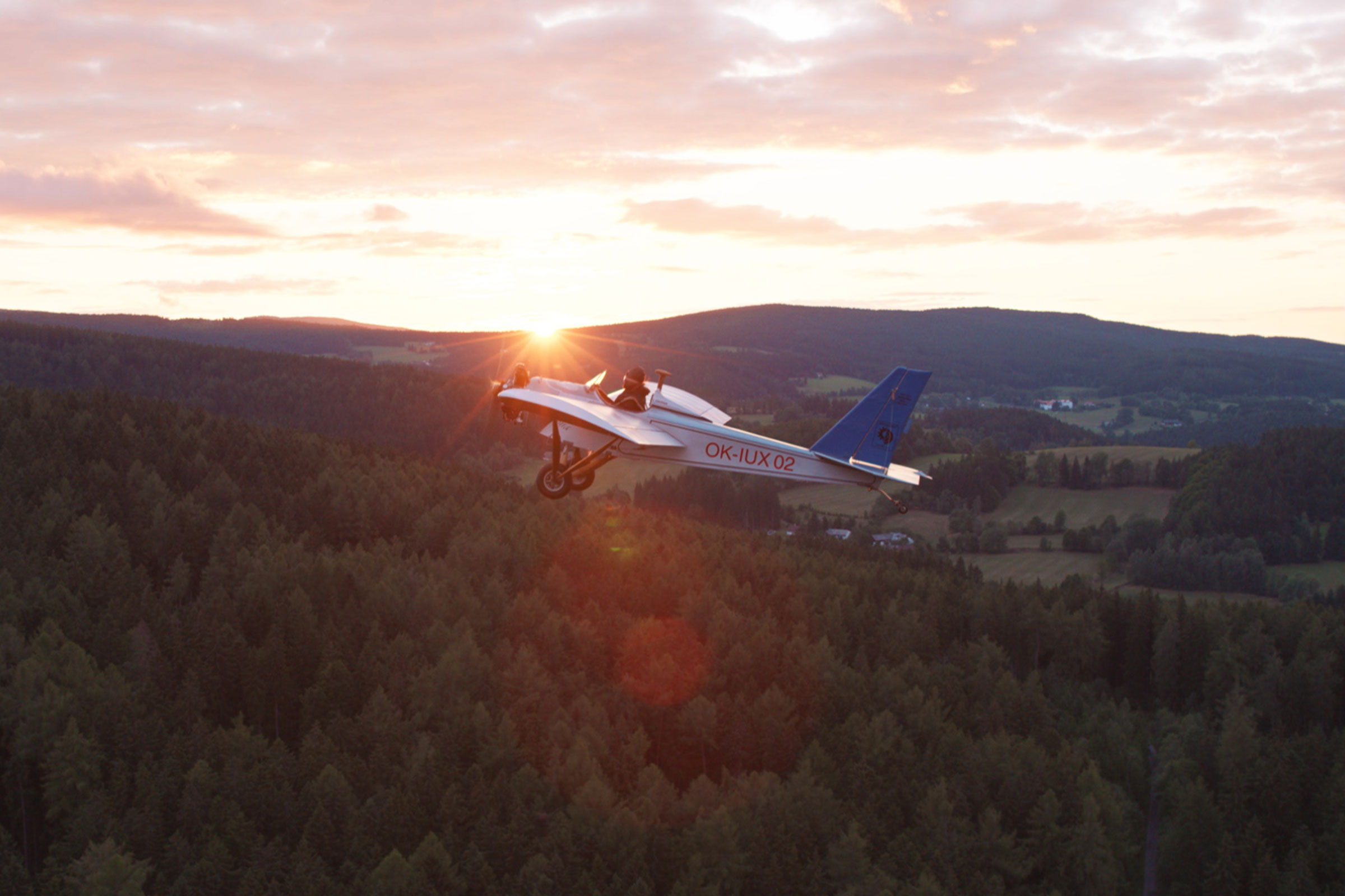 Petit avion volant au-dessus de la forêt au coucher du soleil