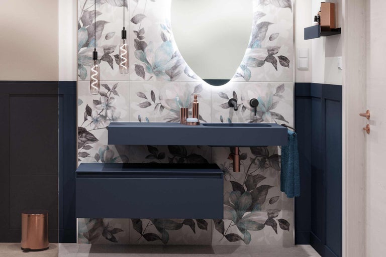 Salle de bains moderne avec meuble-lavabo bleu, miroir avec éclairage et carrelage à motifs floraux