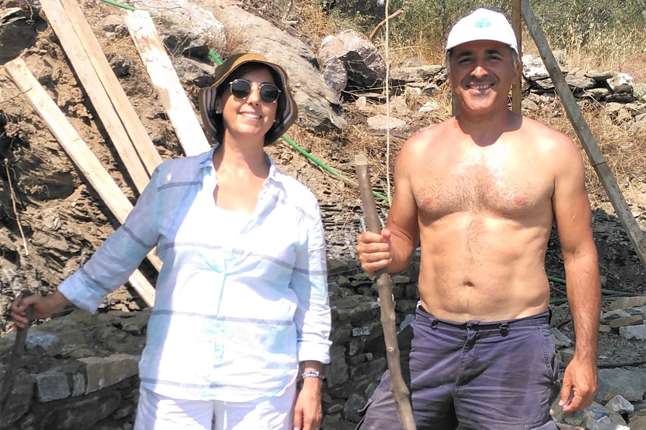 Femme et homme construisent un mur en pierres sèches avec des pierres et du bois