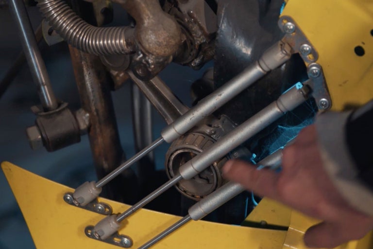 Vue détaillée d'un appareil jaune avec des entretoises métalliques et un roulement touché par une main.