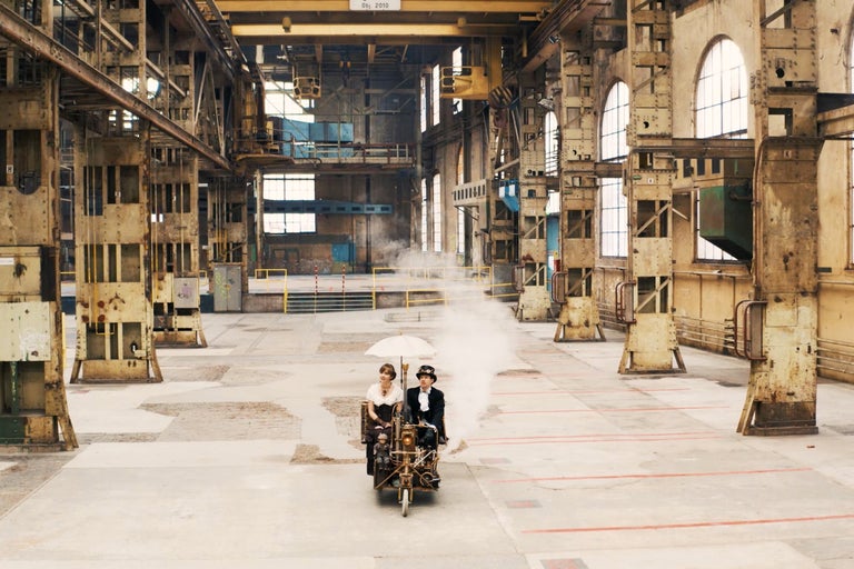 Deux personnes conduisent un véhicule fait maison dans un ancien hall d'usine.