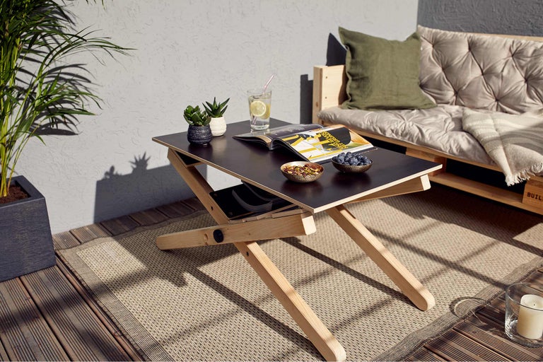 Scène d'extérieur avec une table en bois, des collations, des boissons et un canapé en palettes sur un tapis