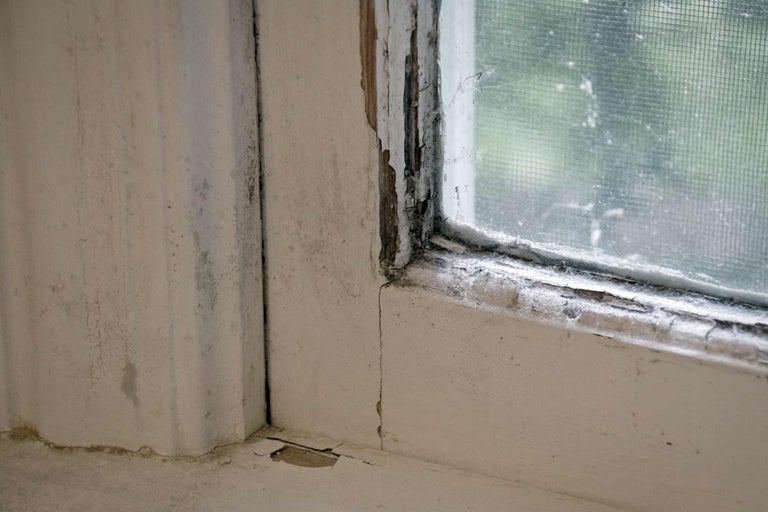 Detailaufnahme eines alten Fensters mit abblätternder Farbe und Beschädigungen