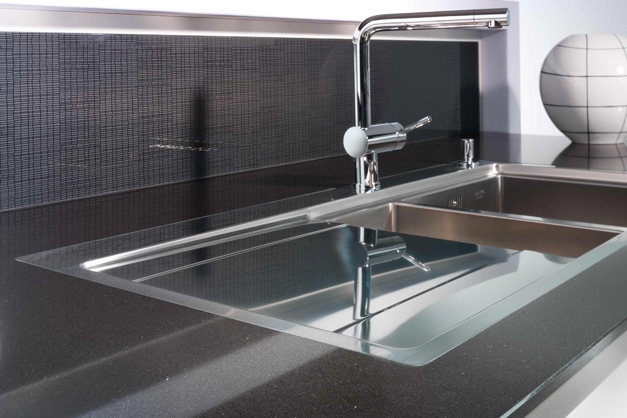 Évier en acier inoxydable avec robinet sur un plan de travail foncé