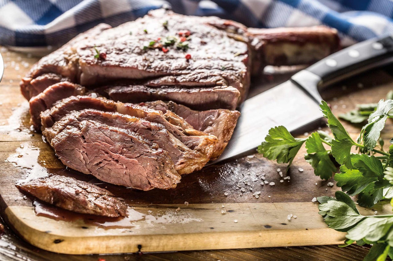 Steak Tomahawk, tranché, sur planche en bois avec couteau et persil
