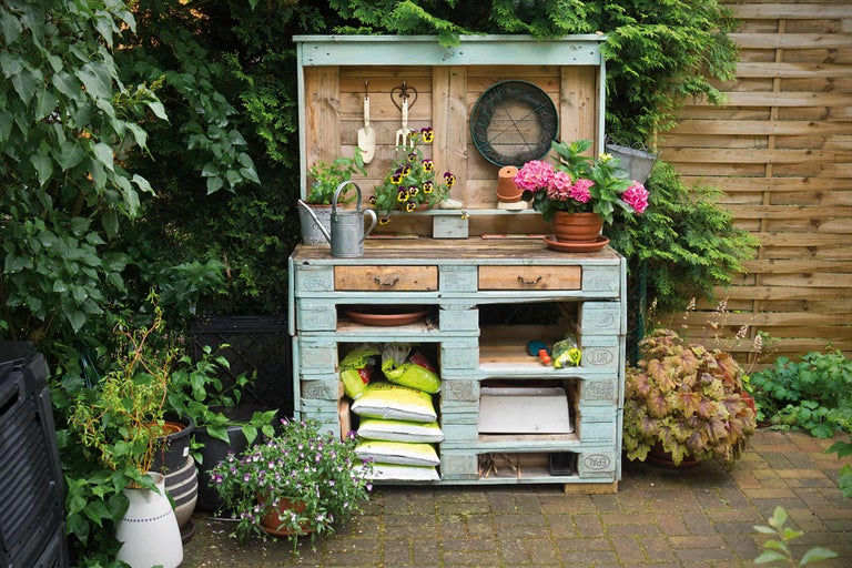 Gartenarbeitstisch aus Holzpaletten mit Gartengeräten und Pflanzen