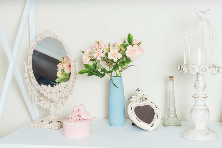 Arrangement décoratif avec miroir, fleurs dans un vase, boîte à bijoux, cadre photo et chandelier