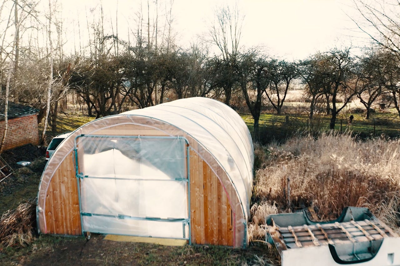 Serre avec cadre en bois et film transparent dans un jardin.