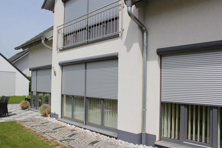 Hausfassade mit heruntergelassenen Rollläden