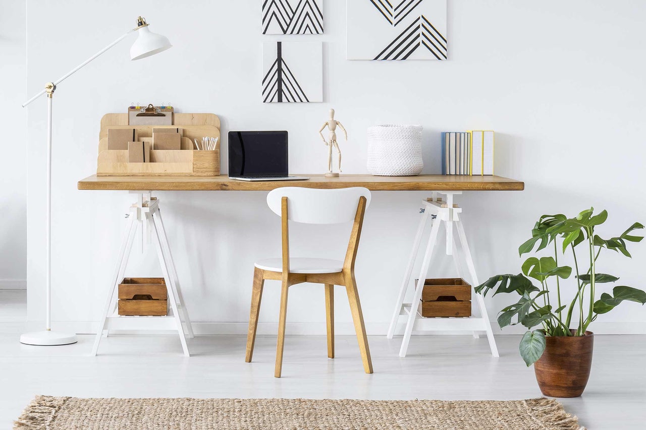 Helles Arbeitszimmer mit Schreibtisch, Stuhl, Stehlampe und Zimmerpflanze