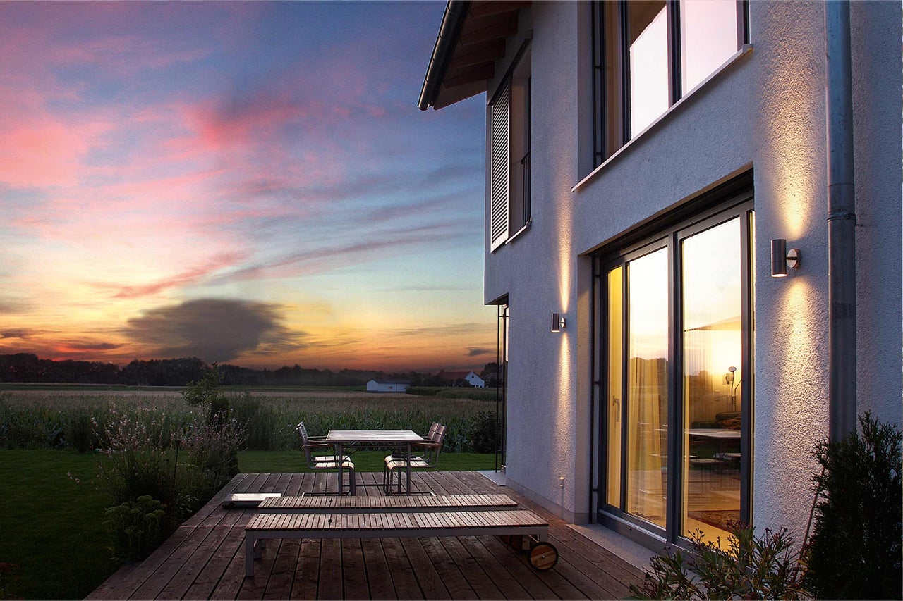 Vue extérieure d'une maison moderne avec terrasse et mobilier de jardin au coucher du soleil