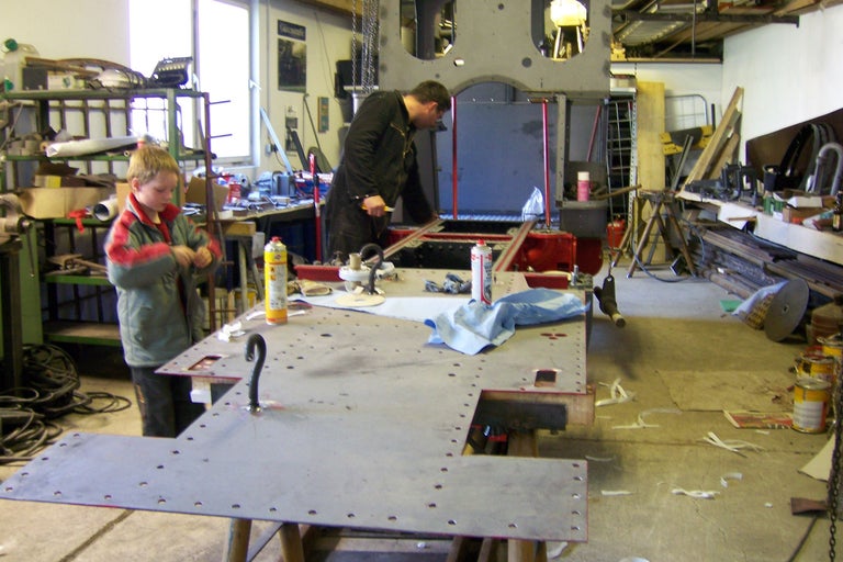 Werkstatt mit Mann, Junge und Werkbank mit Metallplatte