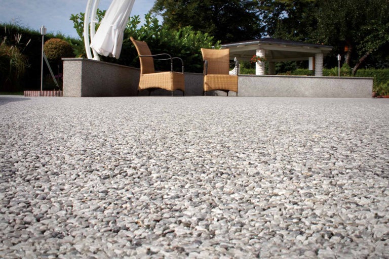 Jardin avec sol en gravier, pavillon de jardin et chaises en osier