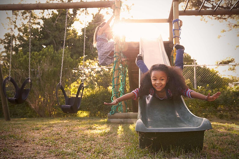 Scène de terrain de jeu avec un enfant sur un toboggan et une balançoire en arrière-plan