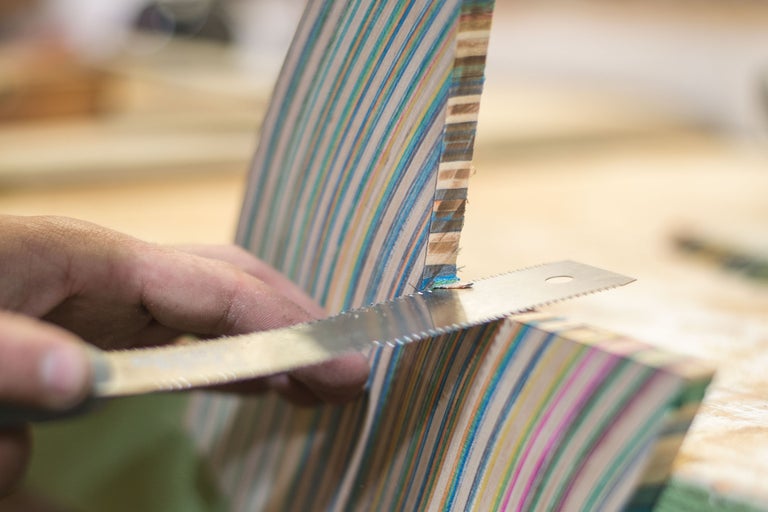 Handwerkliches Sägen eines mehrfarbigen Holzstücks mit einer Metallsäge