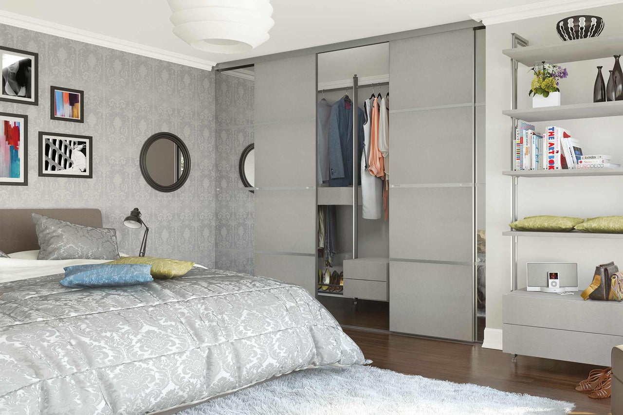 Schlafzimmer mit Bett, Schiebetürenschrank und Regalen für eine organisierte Aufbewahrung