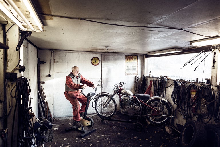 Atelier avec moto ancienne et homme sur vélo d'appartement