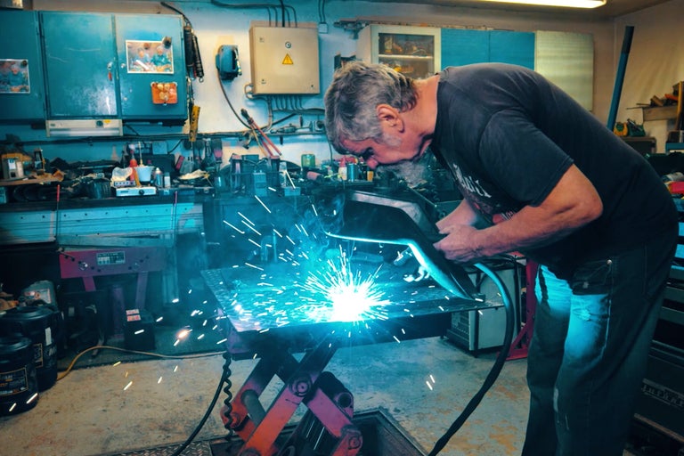 Mann schweißt Metall in einer Werkstatt.