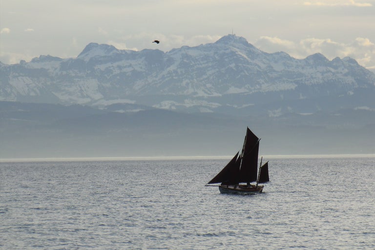 Segelboot auf dem See vor schneebedeckten Bergen