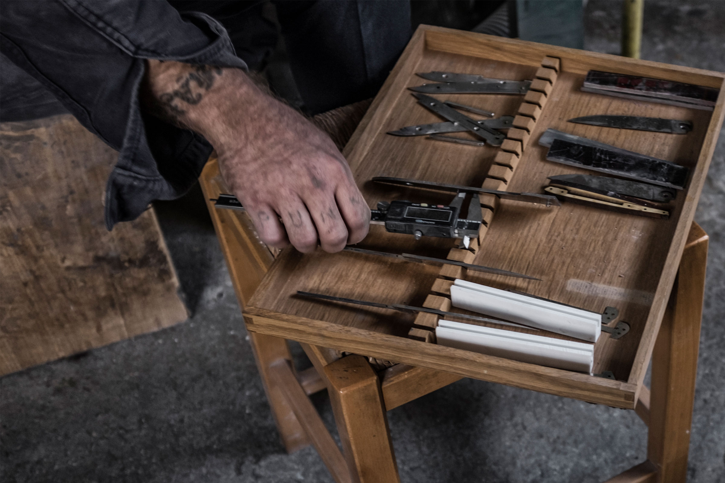 Holzkiste mit verschiedenen Messern und einem Messschieber