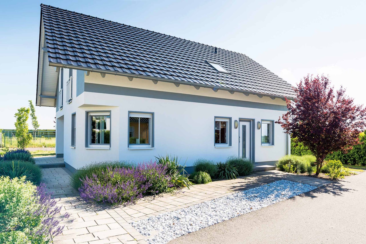 Maison individuelle avec toit à deux pans, fenêtres et allée pavée