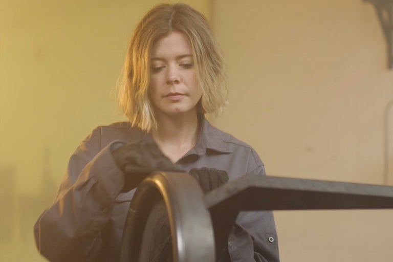 Femme nettoie un objet métallique avec des gants et un chiffon