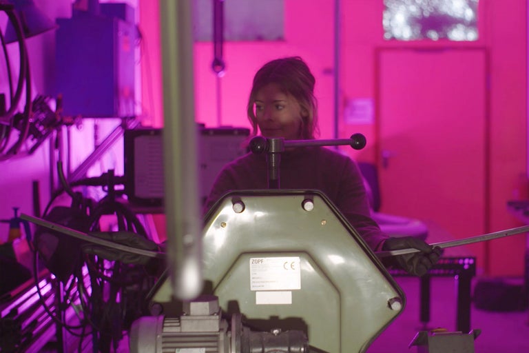 Eine Frau arbeitet mit einer Zopf Biegemaschine in einer Werkstatt.