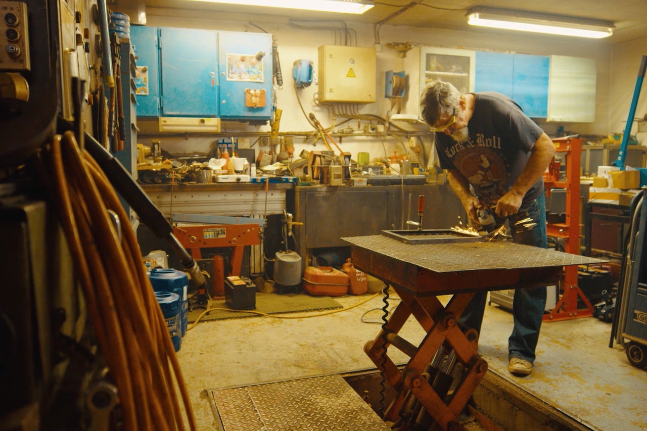 Atelier avec un homme meulant du métal, établi, outils et poste de travail