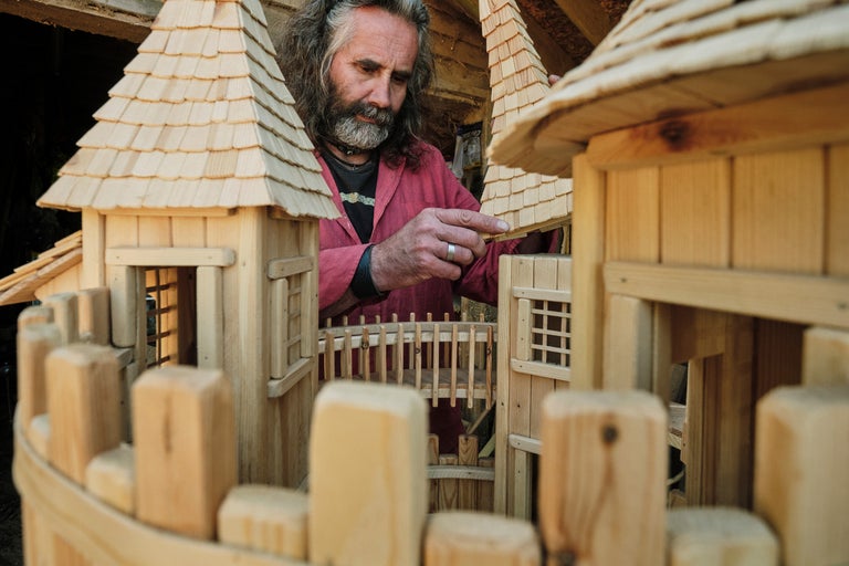 Un homme construit une cabane en bois avec un toit en bardeaux