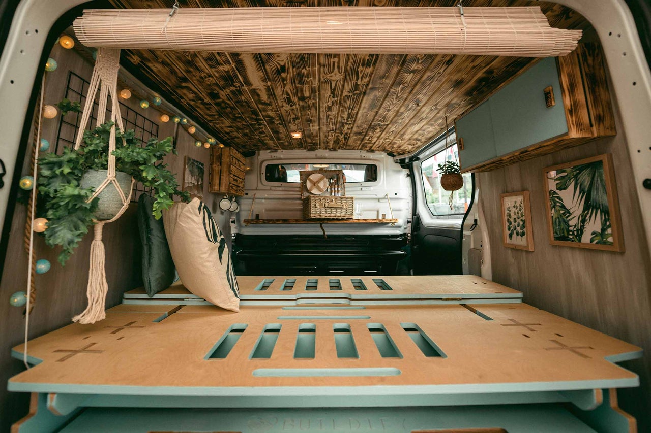 Intérieur d'un van aménagé avec lit en bois, plafond en bois et décorations